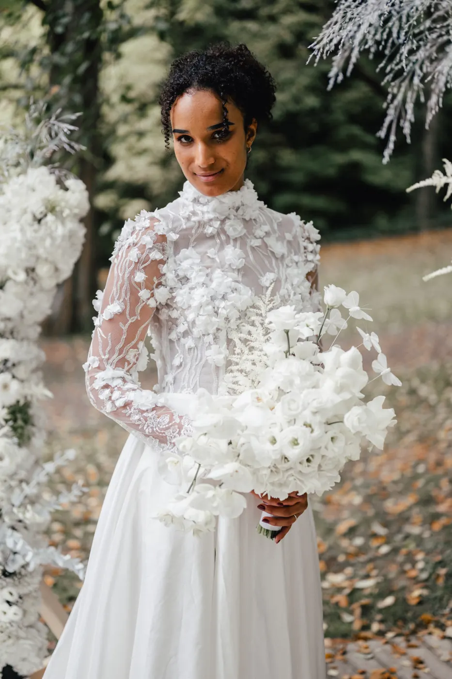 Braut mit weißem Orchideenstrauß und floral besetztem Hochzeitskleid im Freigeist Northeim